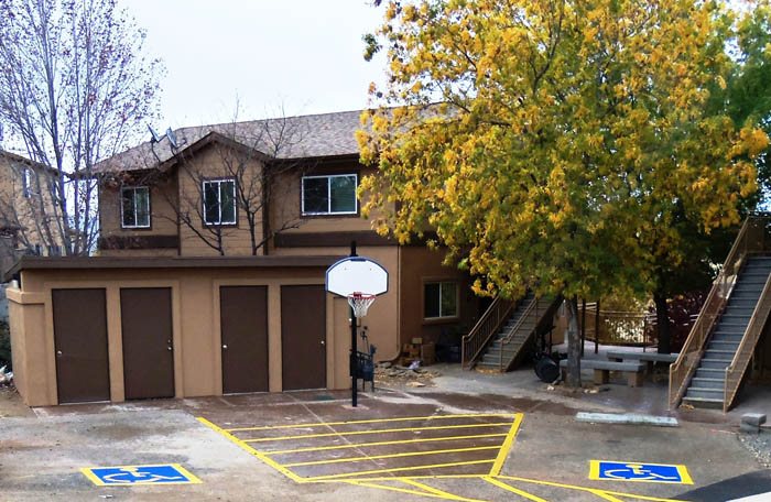 A basketball court with a hoop and two handicap parking spaces.